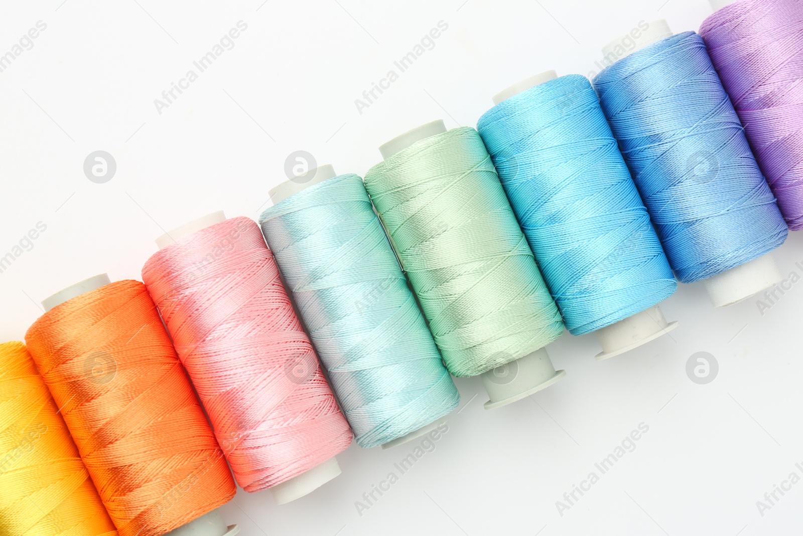 Photo of Spools of sewing threads on white background, flat lay