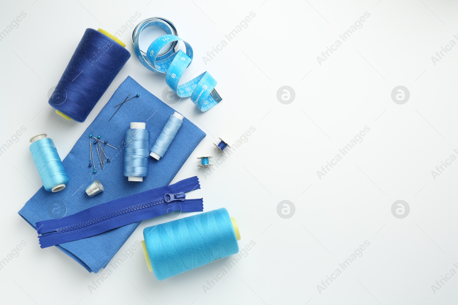 Photo of Flat lay composition with different sewing supplies on white background. Space for text