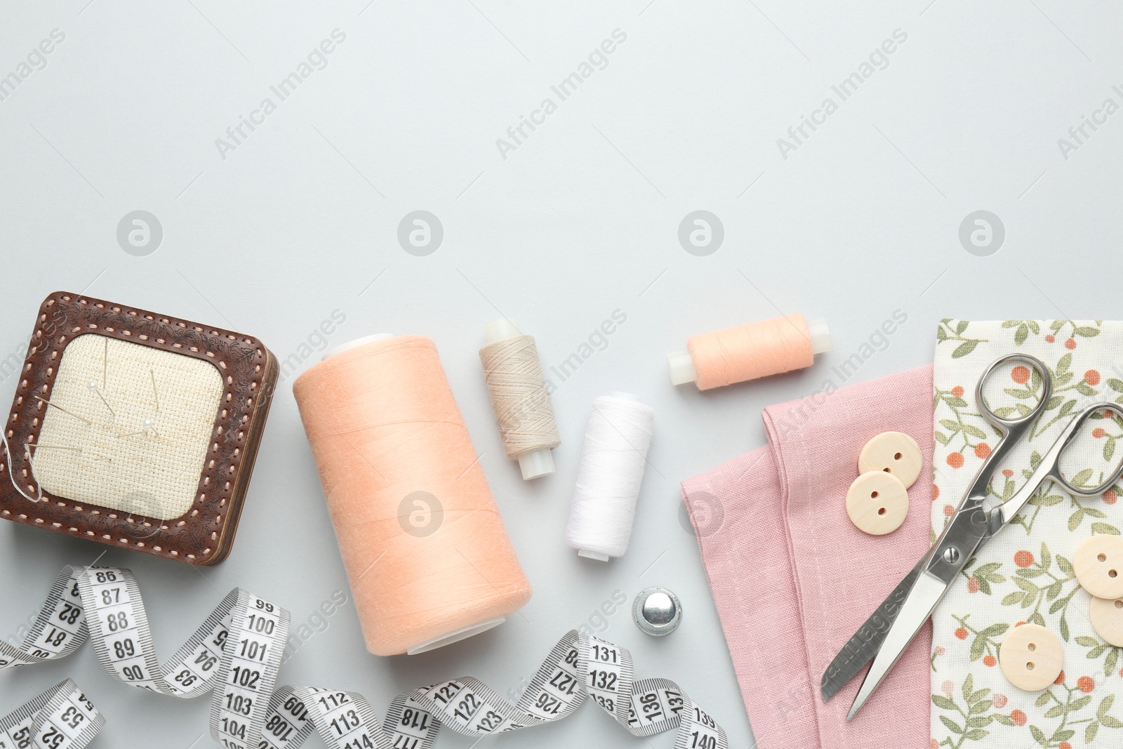 Photo of Flat lay composition with different sewing supplies on light grey background. Space for text