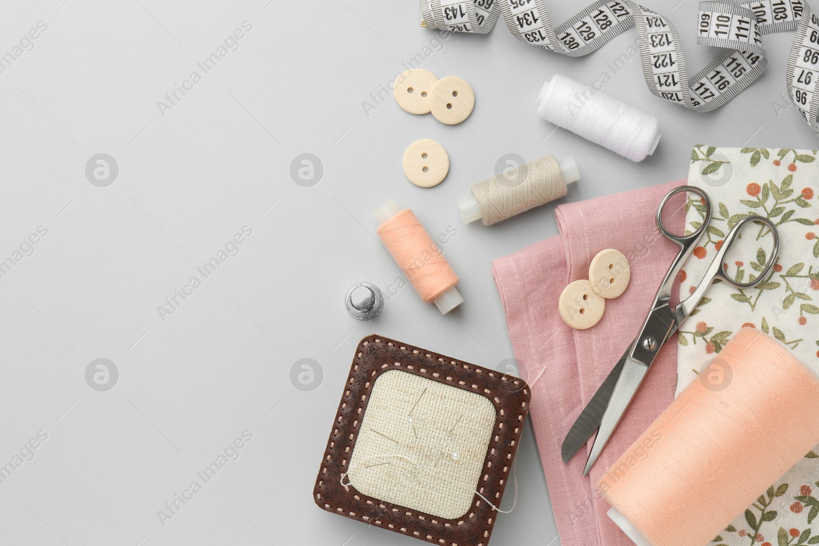 Photo of Flat lay composition with different sewing supplies on light grey background. Space for text