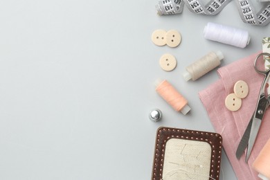 Photo of Flat lay composition with different sewing supplies on light grey background. Space for text