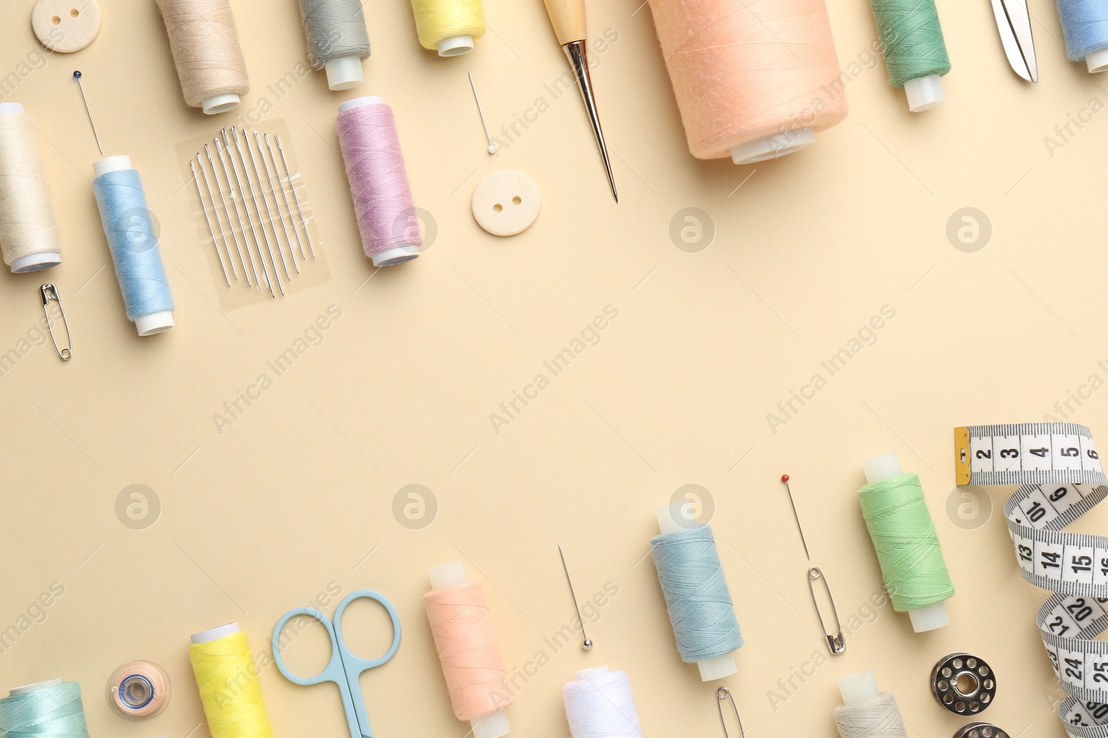 Photo of Flat lay composition with different sewing supplies on beige background. Space for text