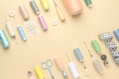 Flat lay composition with different sewing supplies on beige background. Space for text