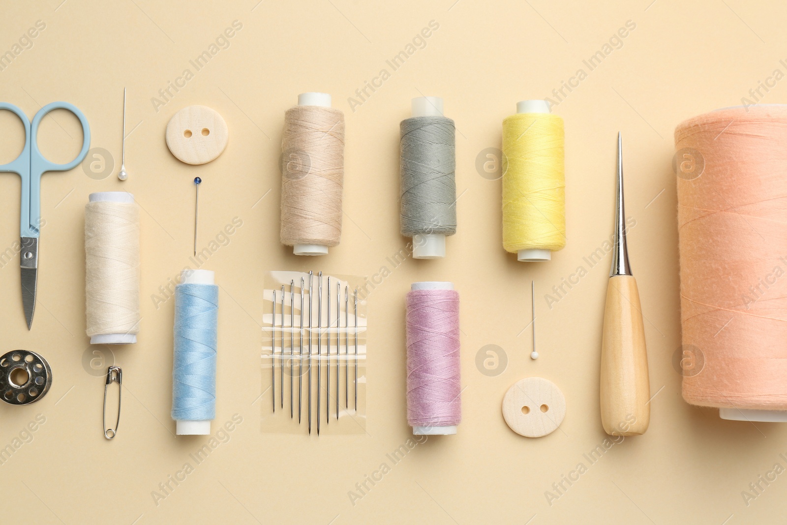 Photo of Flat lay composition with different sewing supplies on beige background