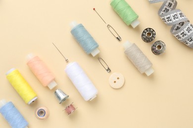 Photo of Flat lay composition with different sewing supplies on beige background