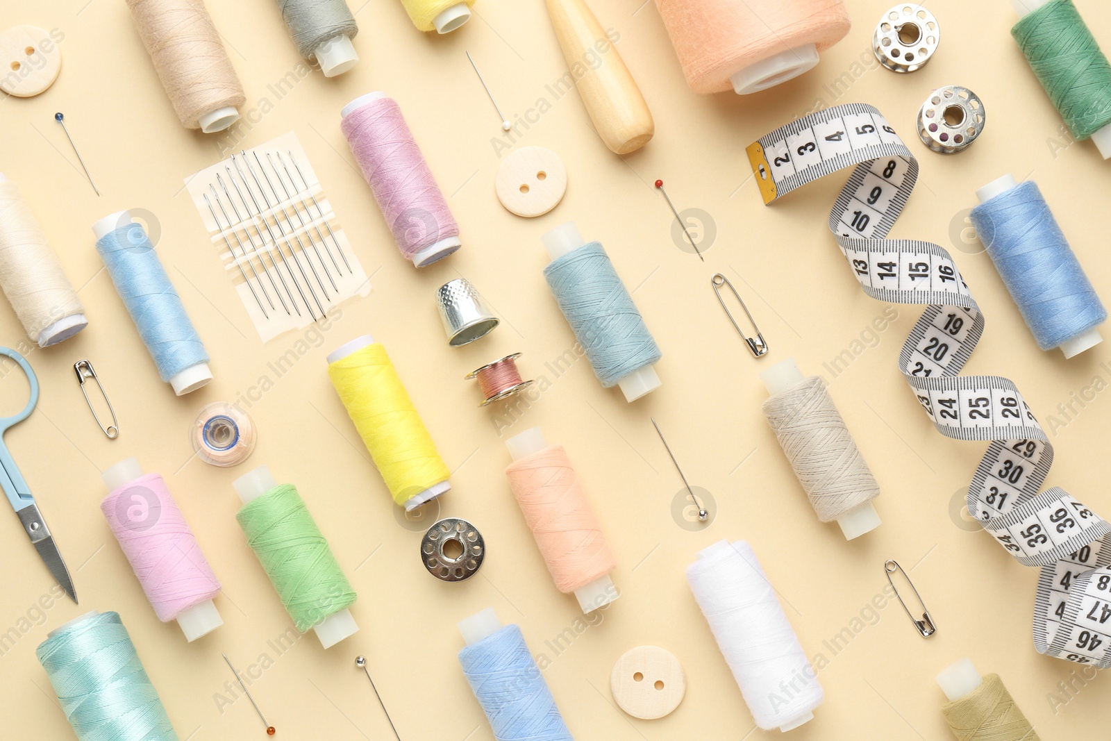 Photo of Flat lay composition with different sewing supplies on beige background