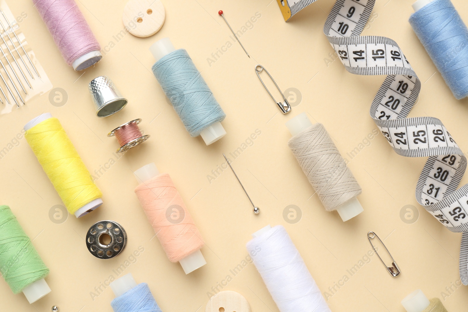 Photo of Flat lay composition with different sewing supplies on beige background