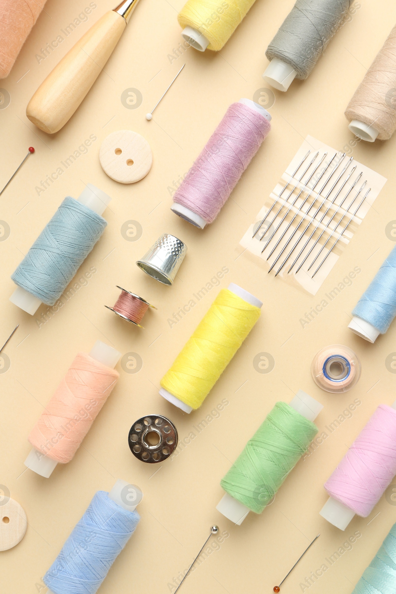 Photo of Flat lay composition with different sewing supplies on beige background