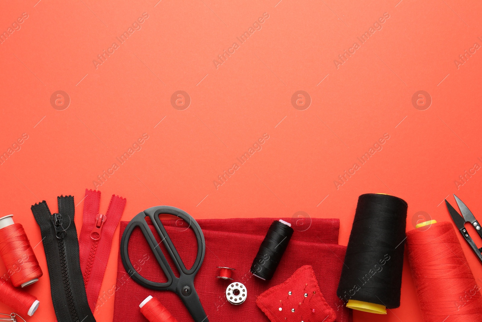 Photo of Flat lay composition with different sewing supplies on coral background. Space for text