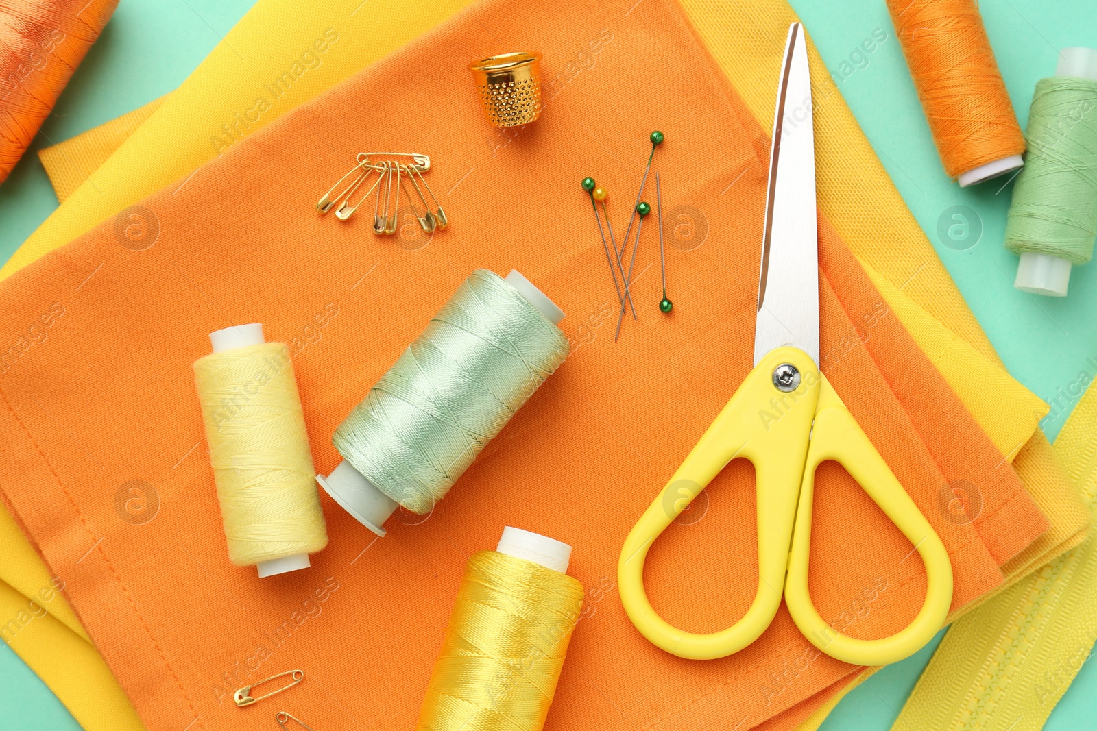 Photo of Flat lay composition with different sewing supplies on turquoise background