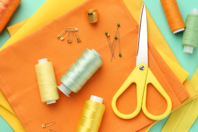 Flat lay composition with different sewing supplies on turquoise background