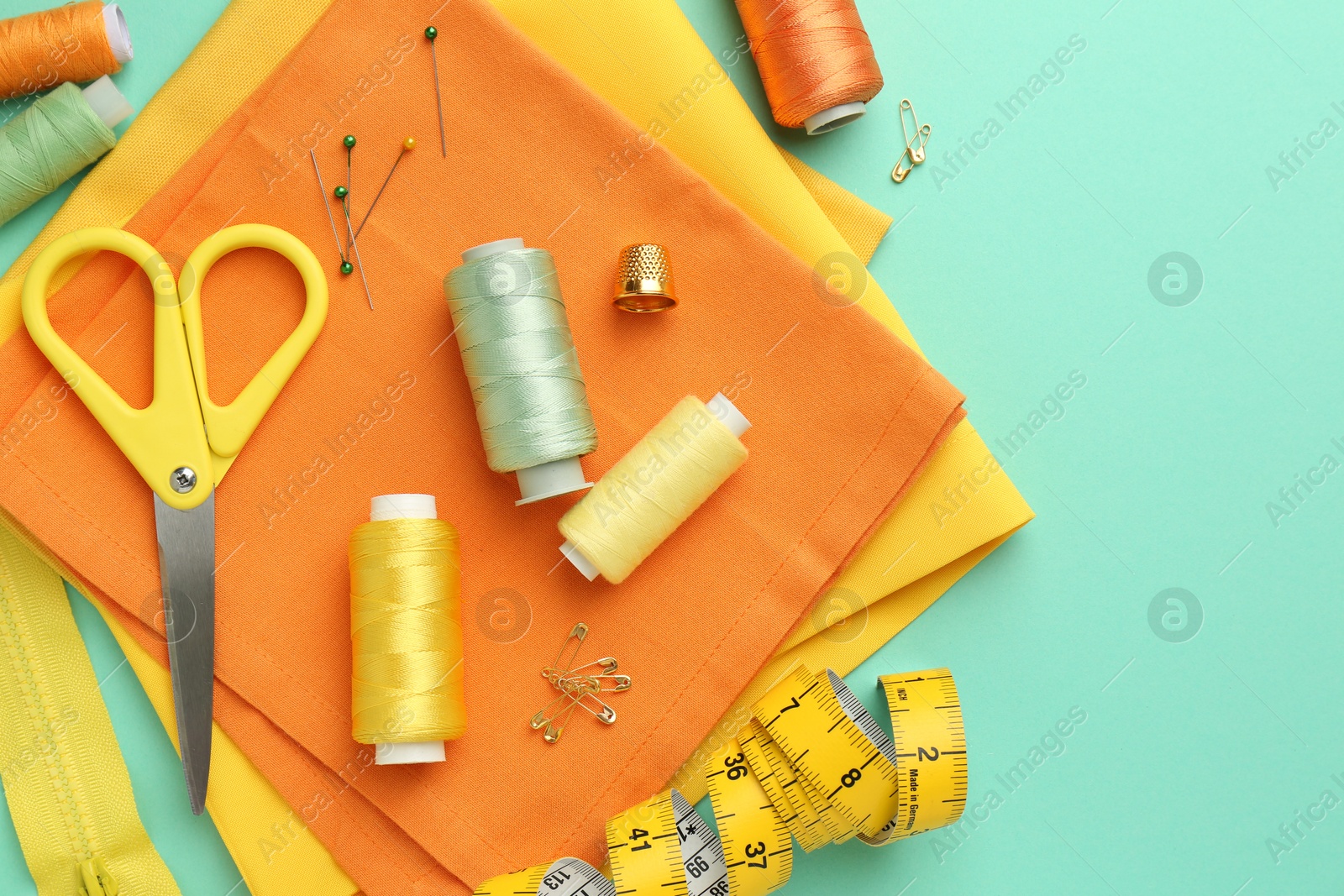 Photo of Flat lay composition with different sewing supplies on turquoise background. Space for text