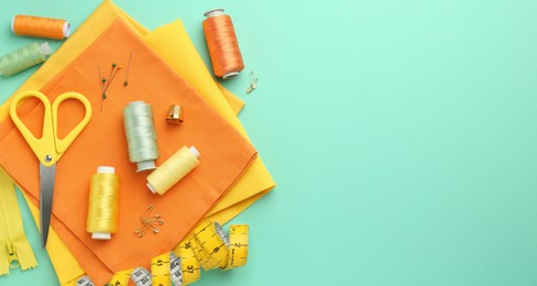 Photo of Flat lay composition with different sewing supplies on turquoise background. Space for text