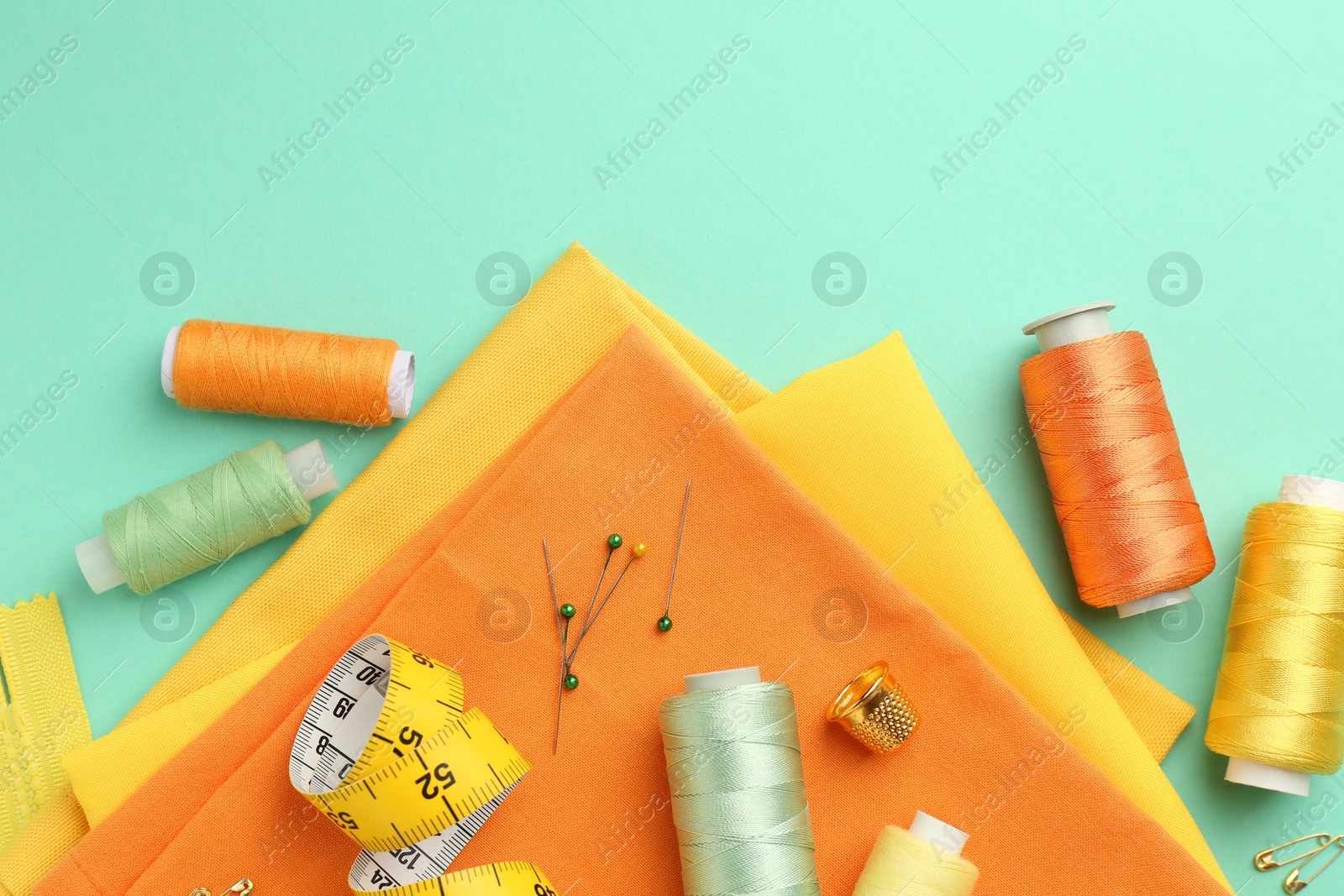 Photo of Flat lay composition with different sewing supplies on turquoise background