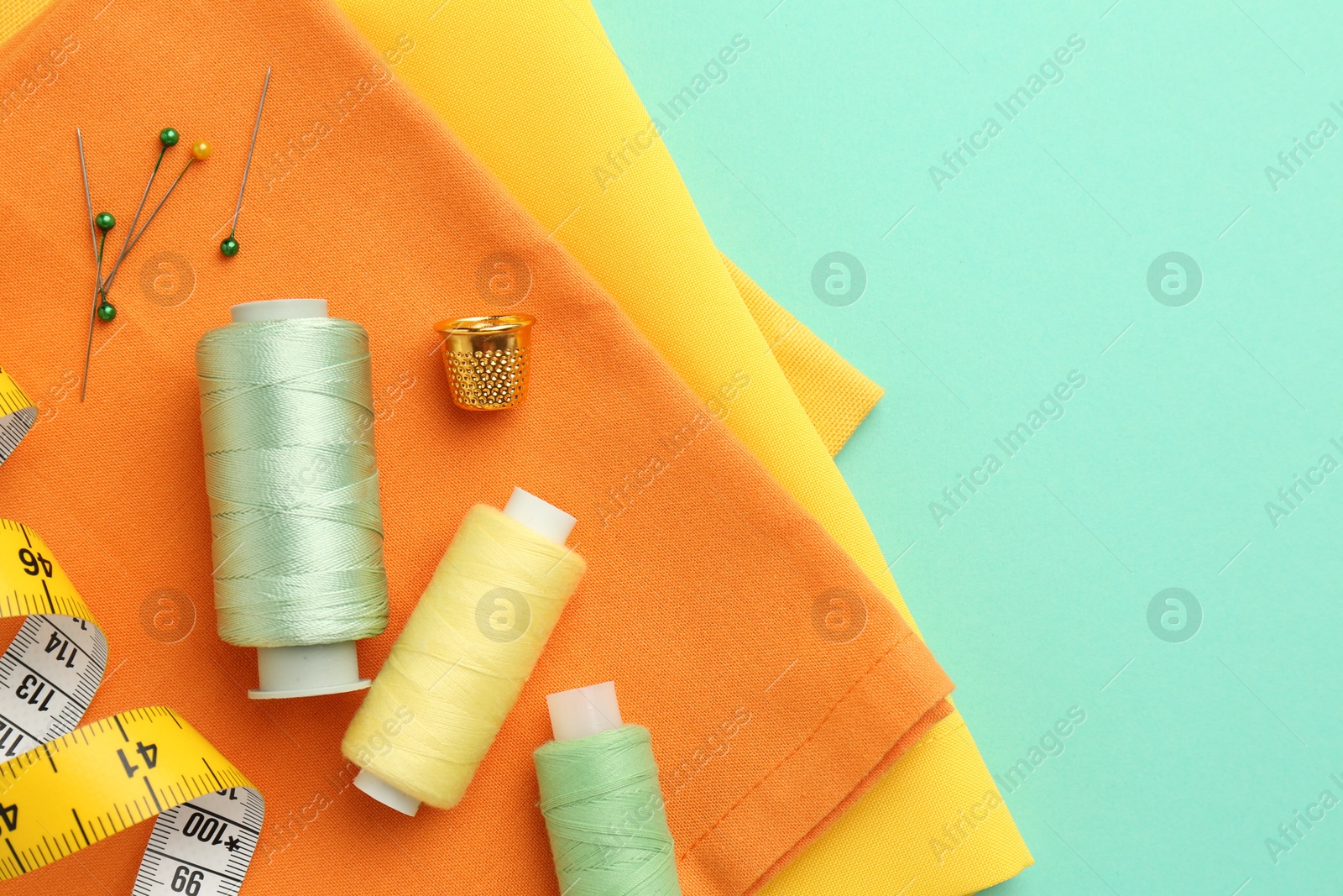 Photo of Flat lay composition with different sewing supplies on turquoise background. Space for text