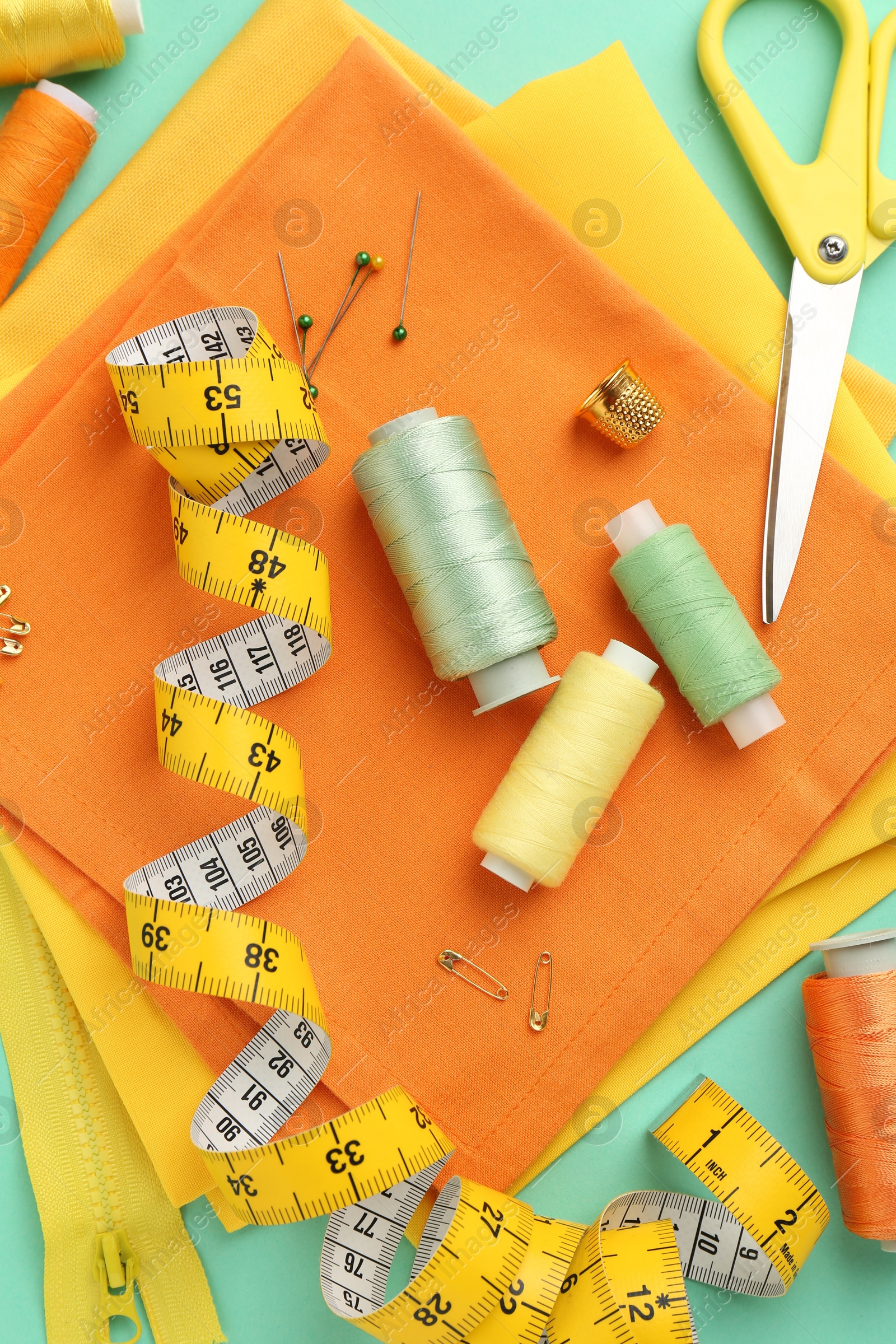 Photo of Flat lay composition with different sewing supplies on turquoise background