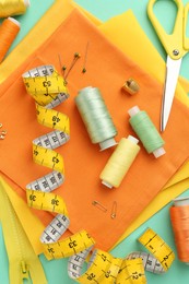 Flat lay composition with different sewing supplies on turquoise background