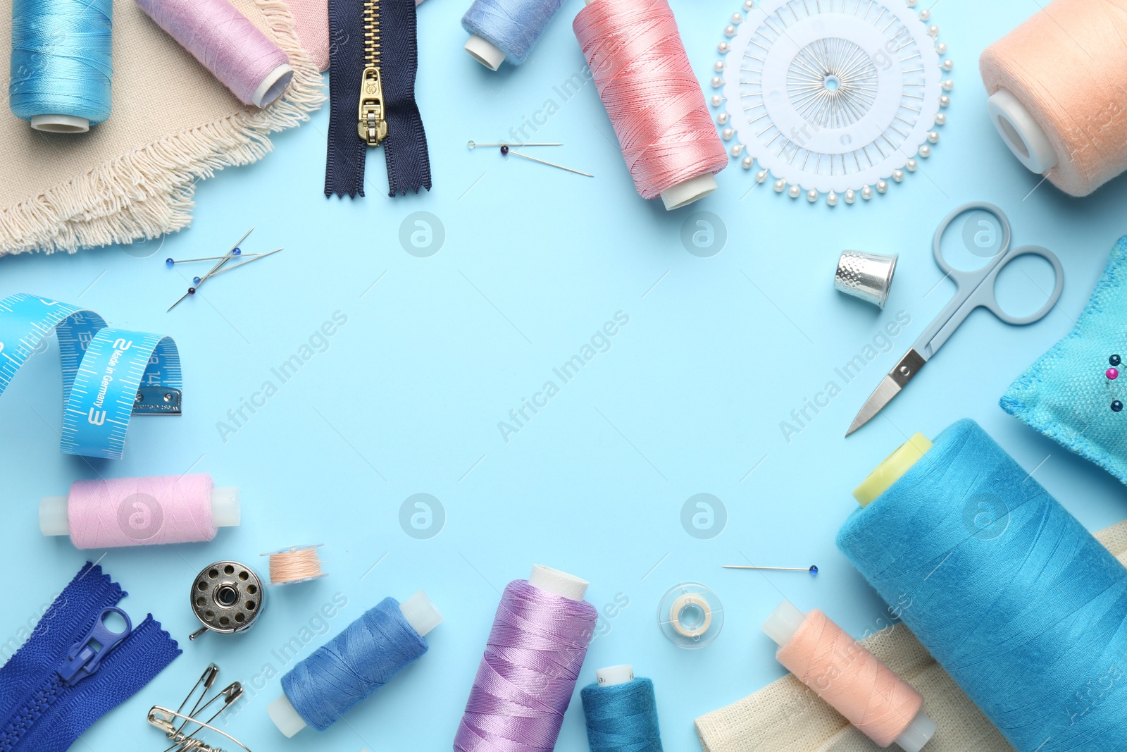 Photo of Frame of different sewing supplies on light blue background, flat lay. Space for text