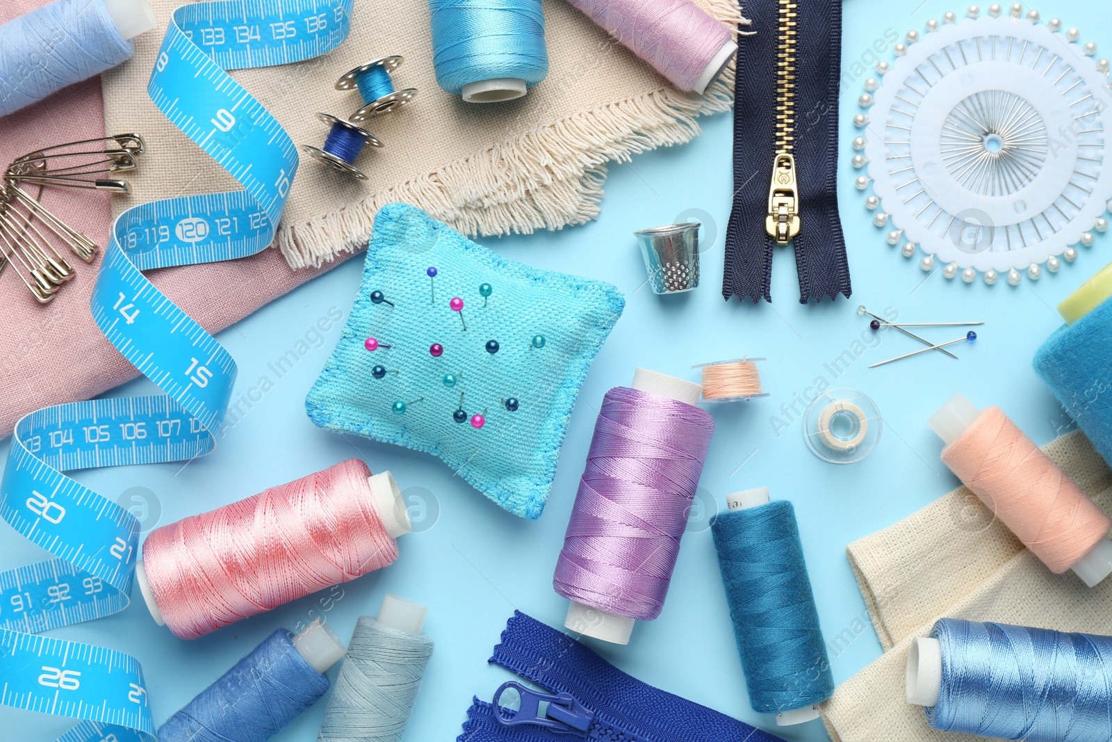 Photo of Flat lay composition with different sewing supplies on light blue background