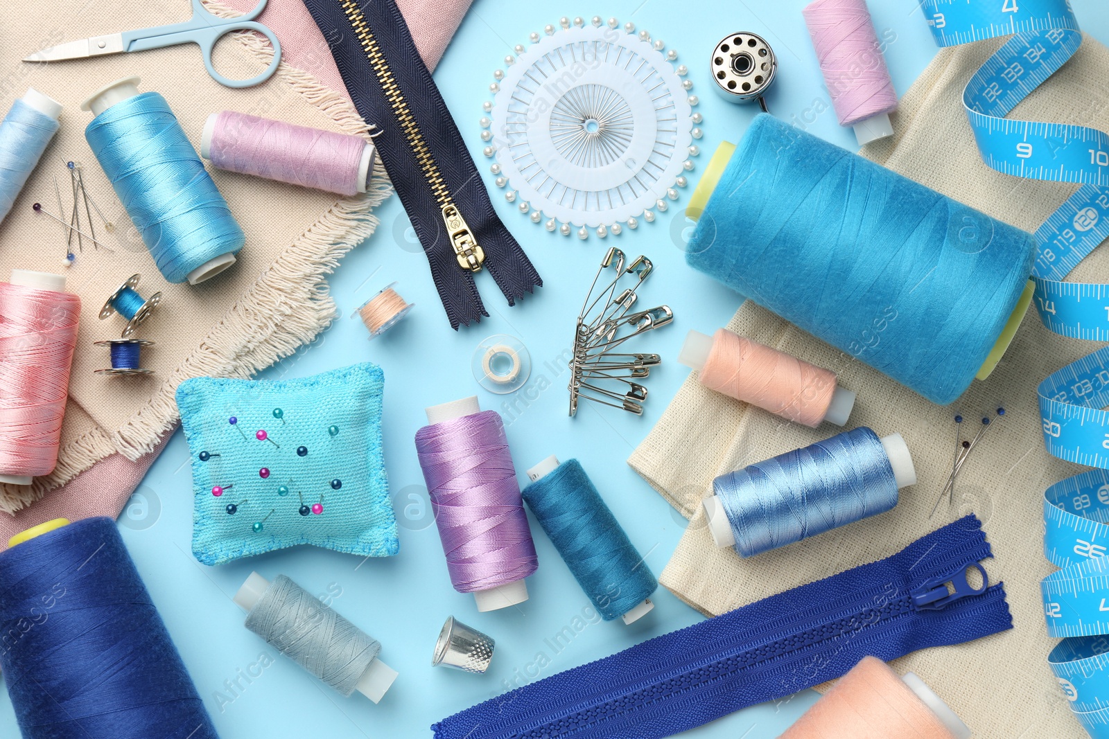 Photo of Flat lay composition with different sewing supplies on light blue background