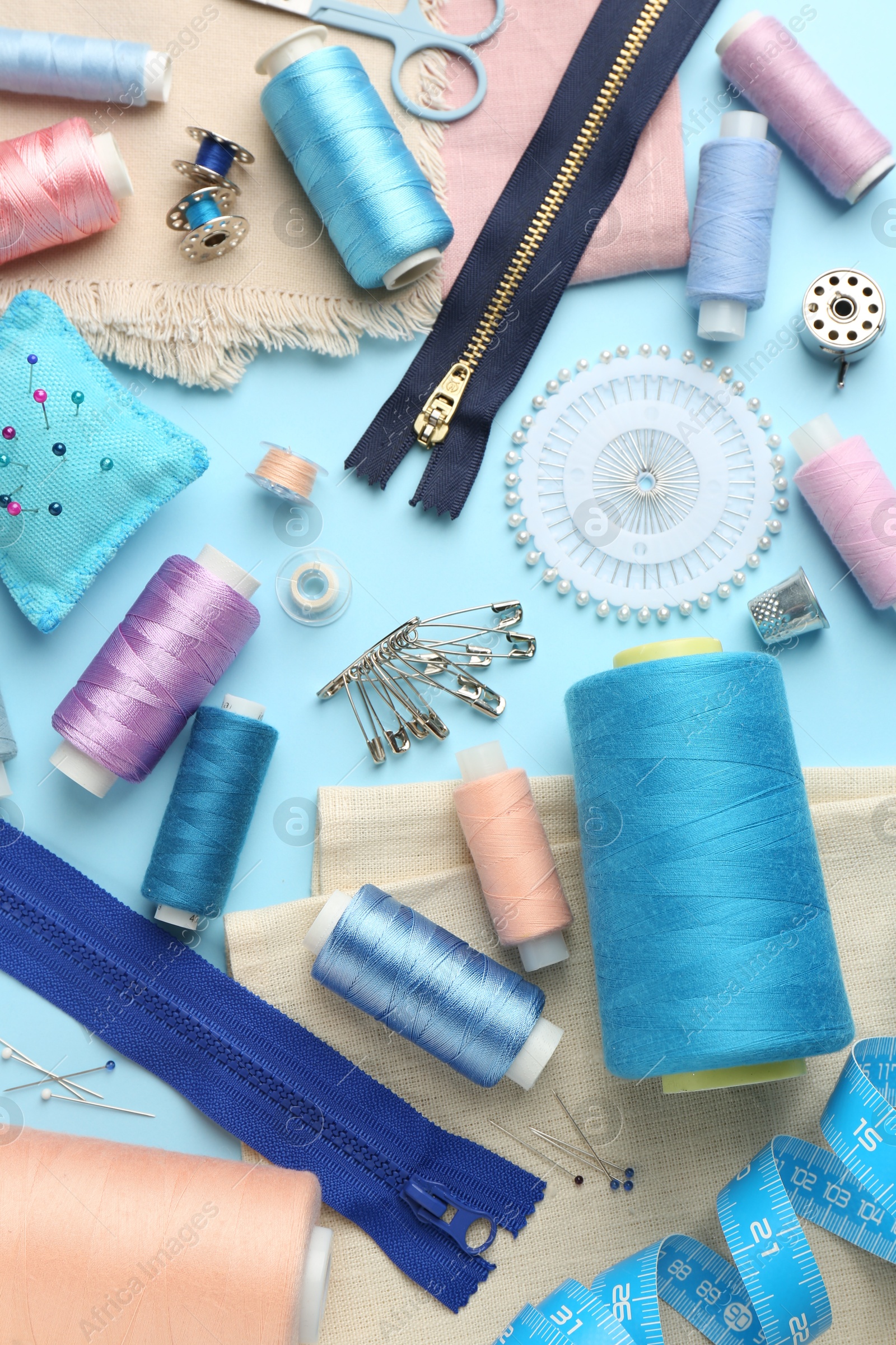 Photo of Flat lay composition with different sewing supplies on light blue background