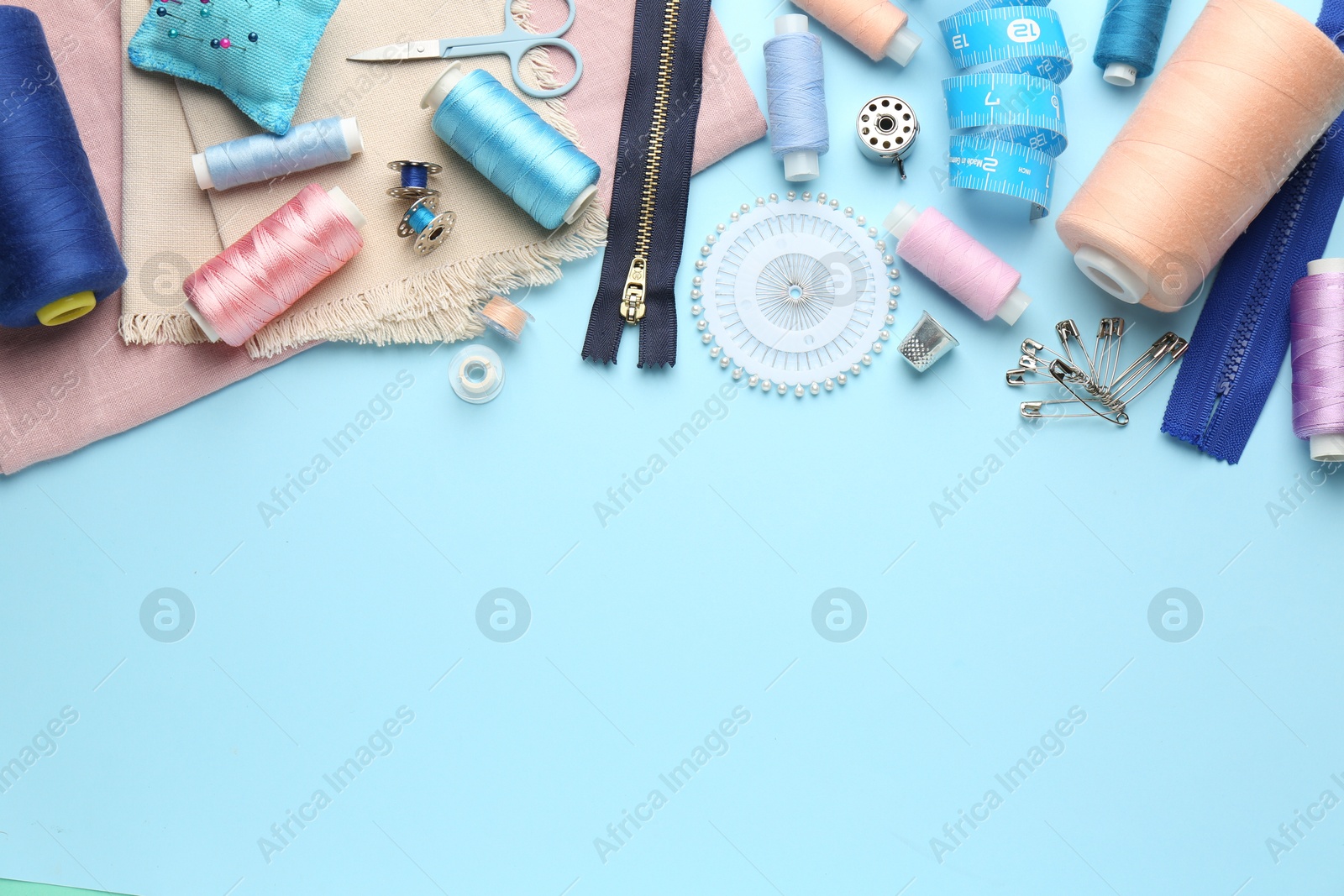 Photo of Flat lay composition with different sewing supplies on light blue background. Space for text