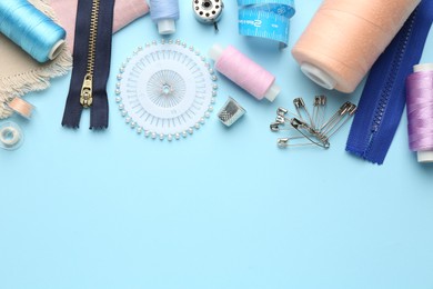 Photo of Flat lay composition with different sewing supplies on light blue background. Space for text