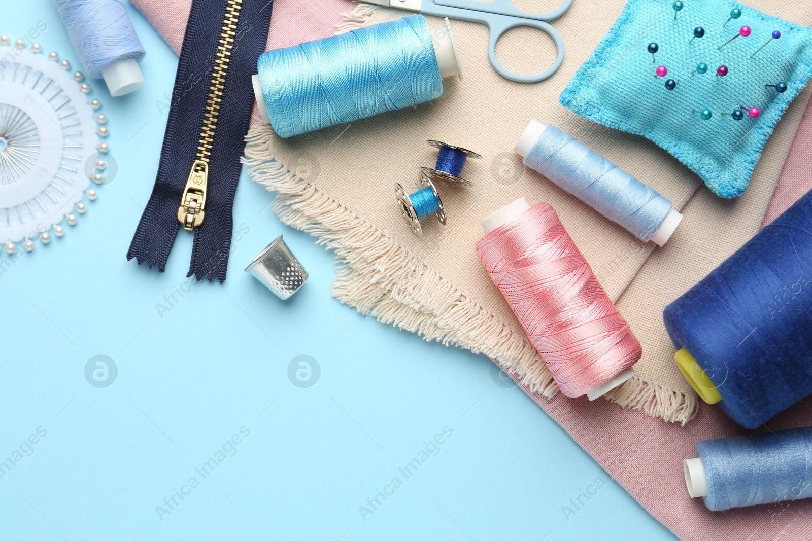 Photo of Flat lay composition with different sewing supplies on light blue background. Space for text