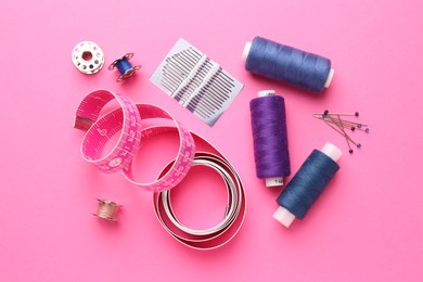 Flat lay composition with different sewing supplies on pink background