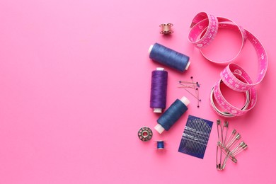 Photo of Flat lay composition with different sewing supplies on pink background. Space for text