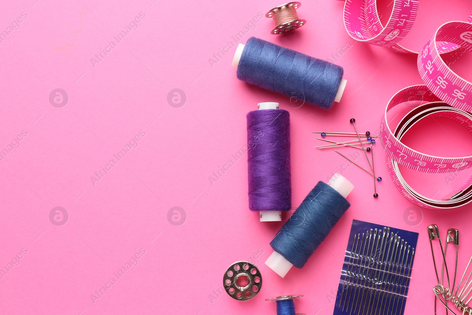 Photo of Flat lay composition with different sewing supplies on pink background. Space for text