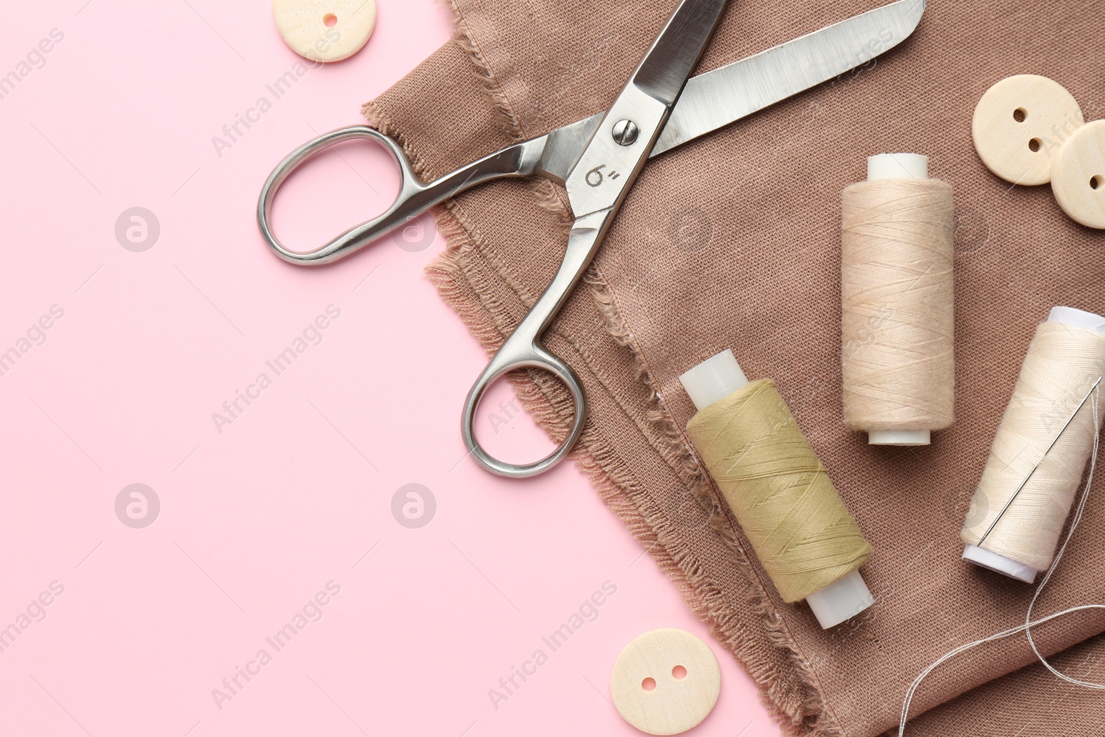 Photo of Flat lay composition with different sewing supplies on pink background. Space for text