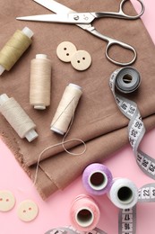 Flat lay composition with different sewing supplies on pink background