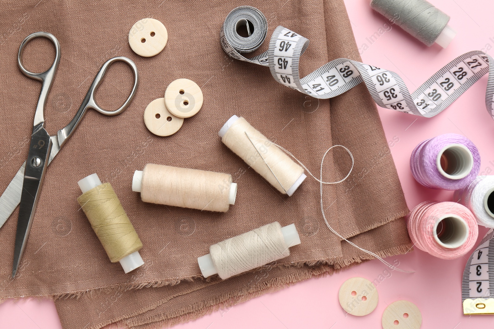 Photo of Flat lay composition with different sewing supplies on pink background