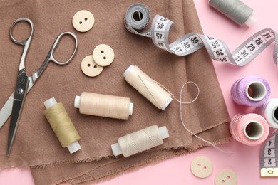 Flat lay composition with different sewing supplies on pink background