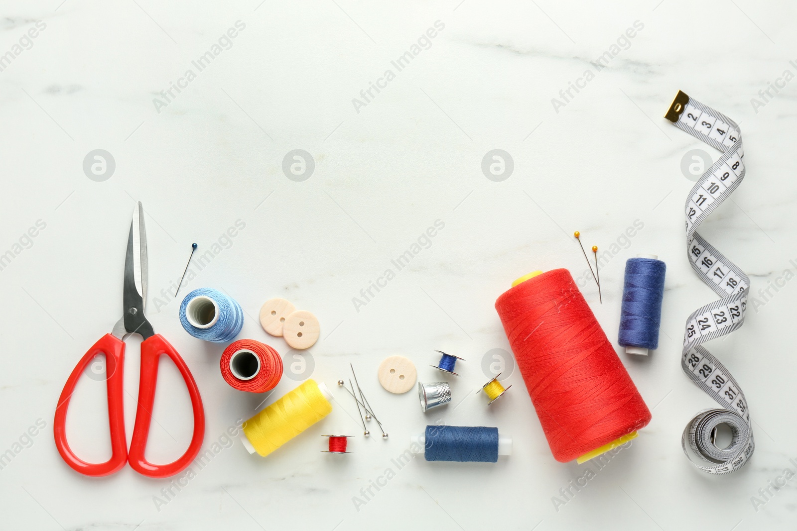 Photo of Flat lay composition with different sewing supplies on white marble table. Space for text