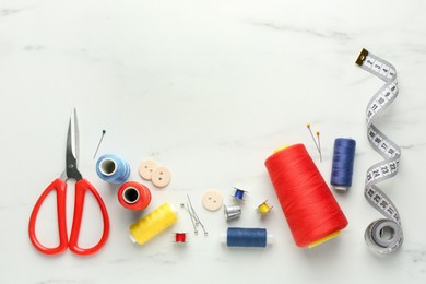 Photo of Flat lay composition with different sewing supplies on white marble table. Space for text