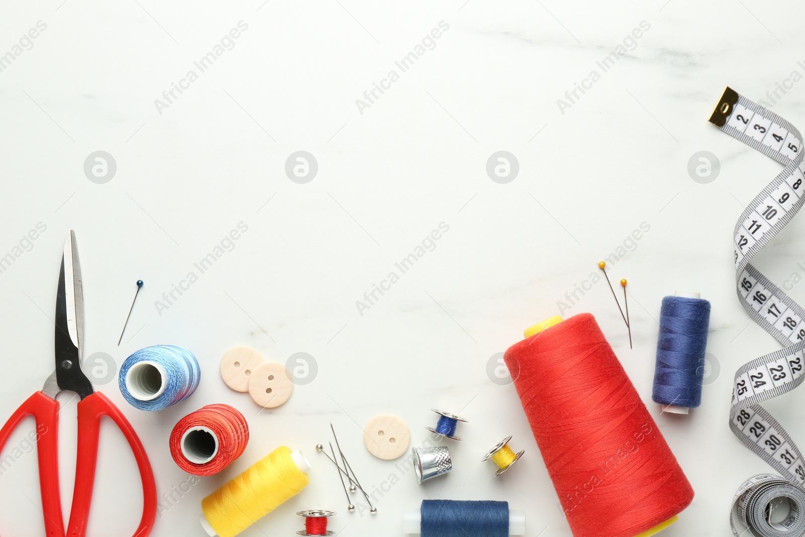 Photo of Flat lay composition with different sewing supplies on white marble table. Space for text