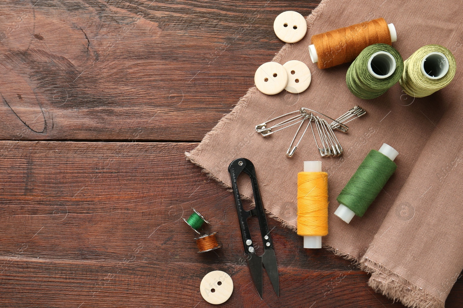 Photo of Flat lay composition with different sewing supplies on wooden table. Space for text