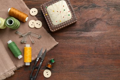 Photo of Flat lay composition with different sewing supplies on wooden table. Space for text