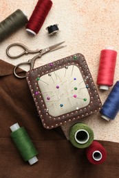 Photo of Flat lay composition with different sewing supplies on beige textured table