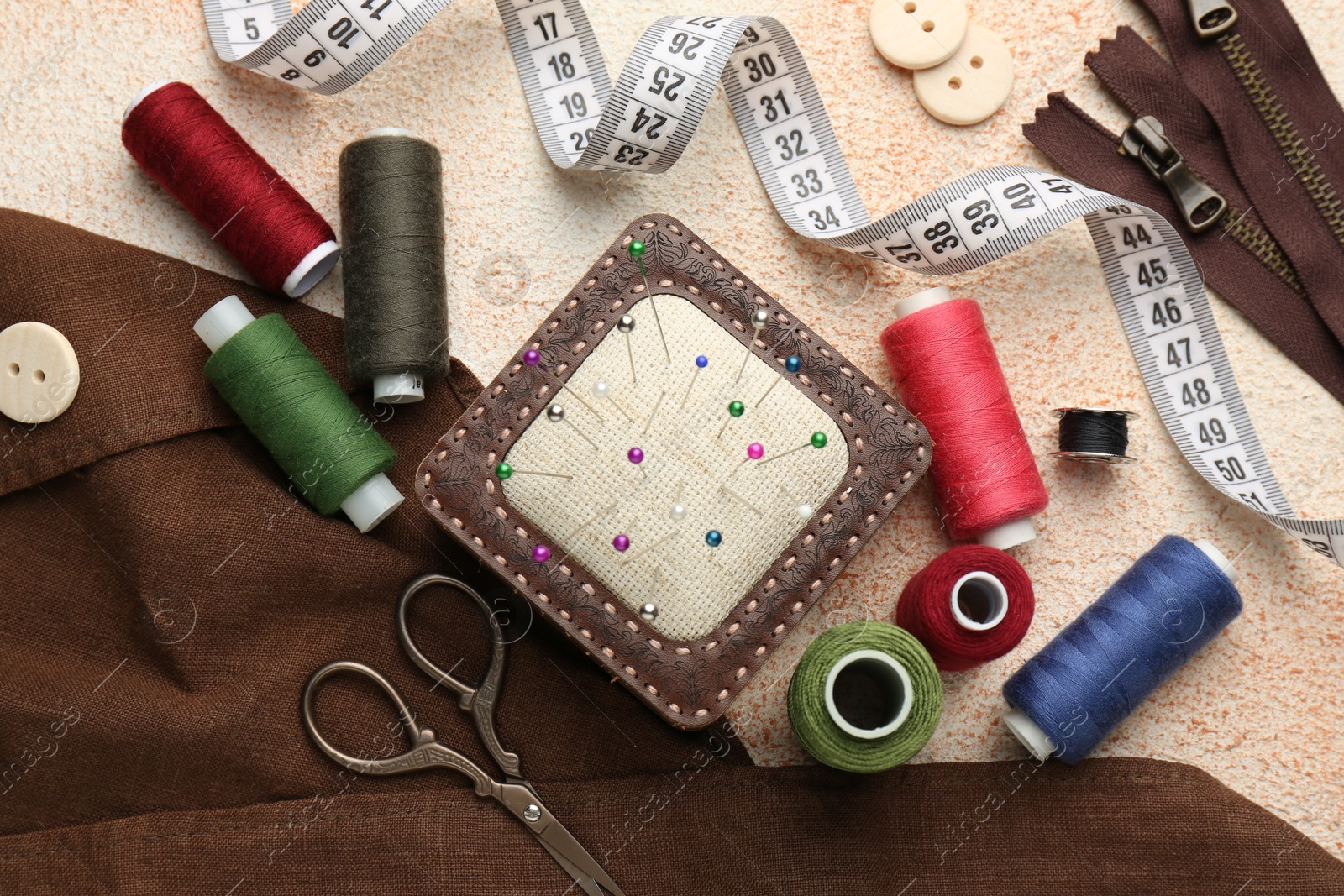 Photo of Flat lay composition with different sewing supplies on beige textured table