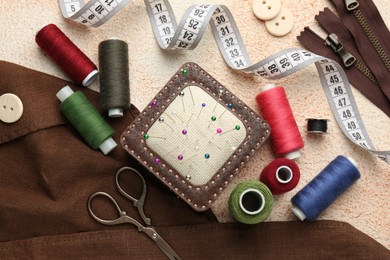 Flat lay composition with different sewing supplies on beige textured table