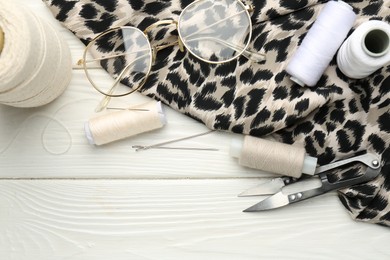 Photo of Flat lay composition with different sewing supplies and glasses on white wooden table