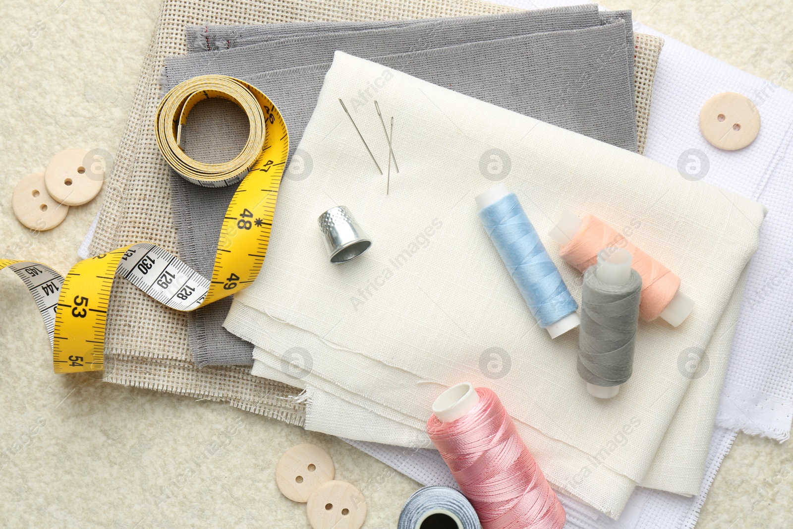 Photo of Flat lay composition with different sewing supplies on light textured table