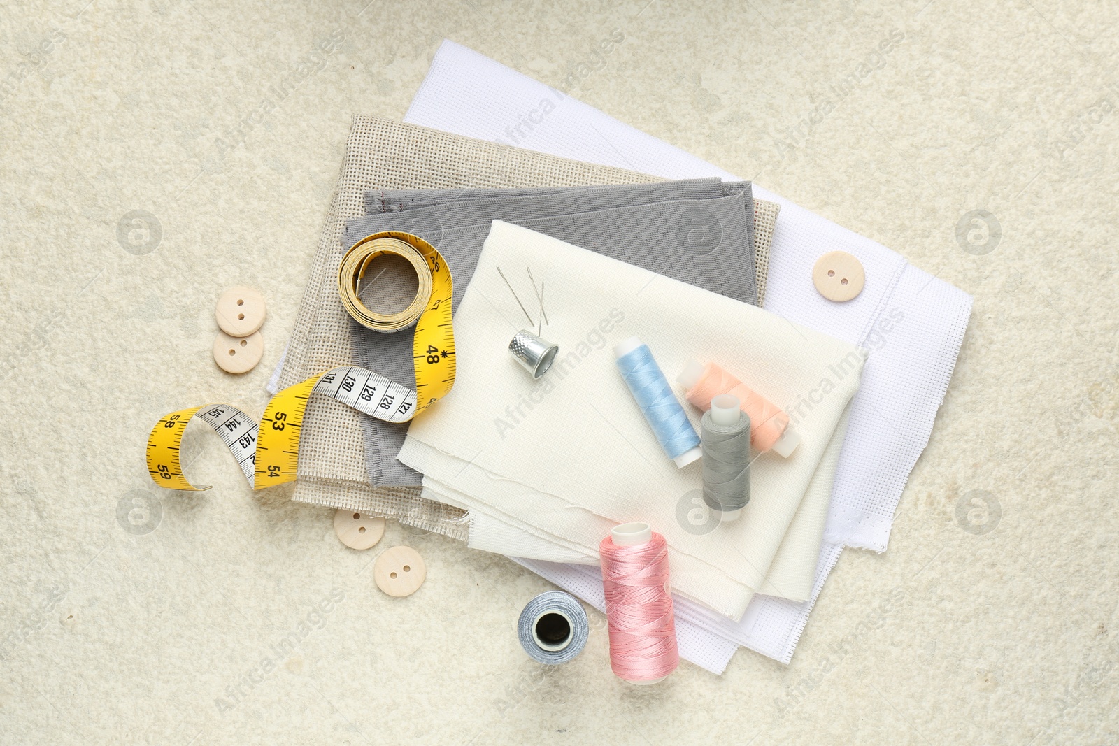 Photo of Flat lay composition with different sewing supplies on light textured table