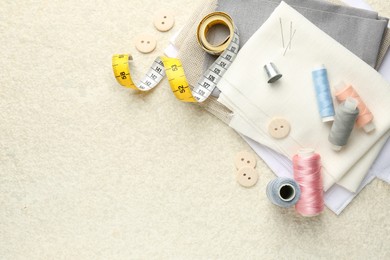 Photo of Flat lay composition with different sewing supplies on light textured table. Space for text