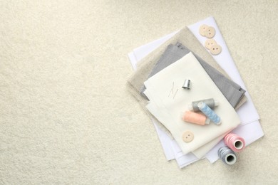 Photo of Different sewing supplies on light textured table, top view. Space for text