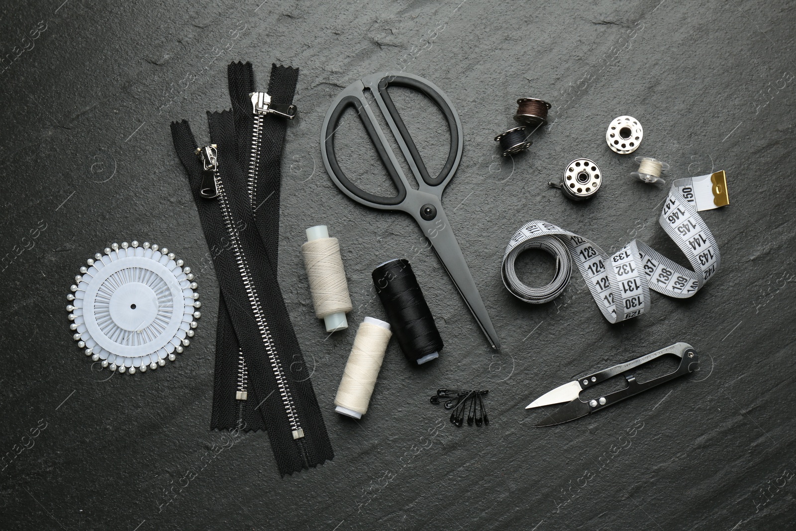 Photo of Flat lay composition with different sewing supplies on dark textured table