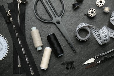 Photo of Flat lay composition with different sewing supplies on dark textured table